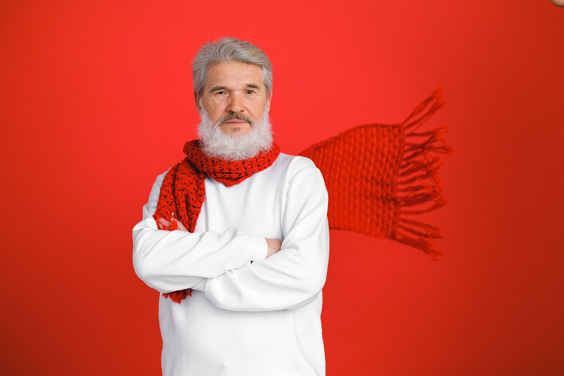 an elderly man in white sweater and red scarf