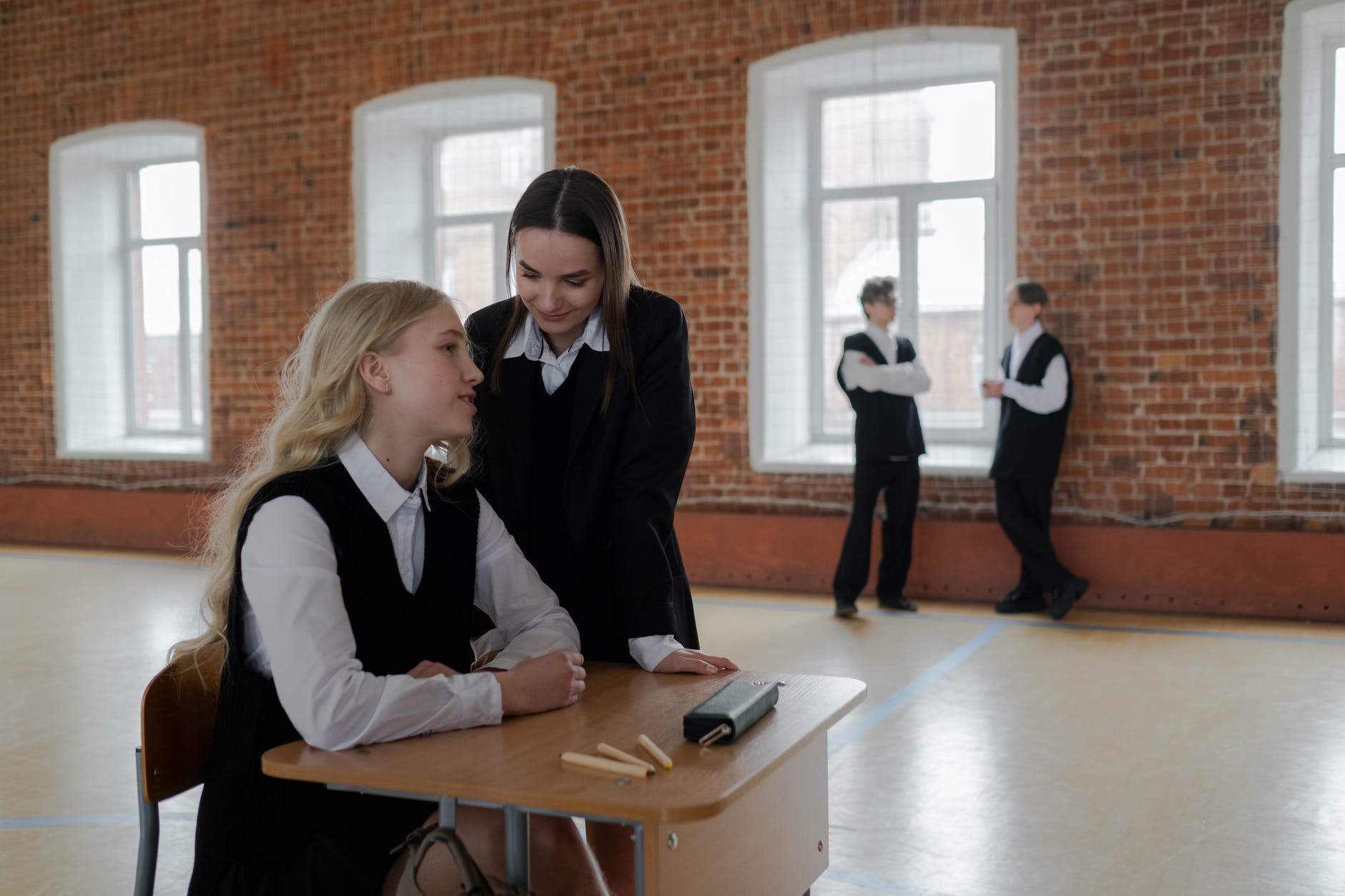 young women in school uniforms having conversation inside the classroom